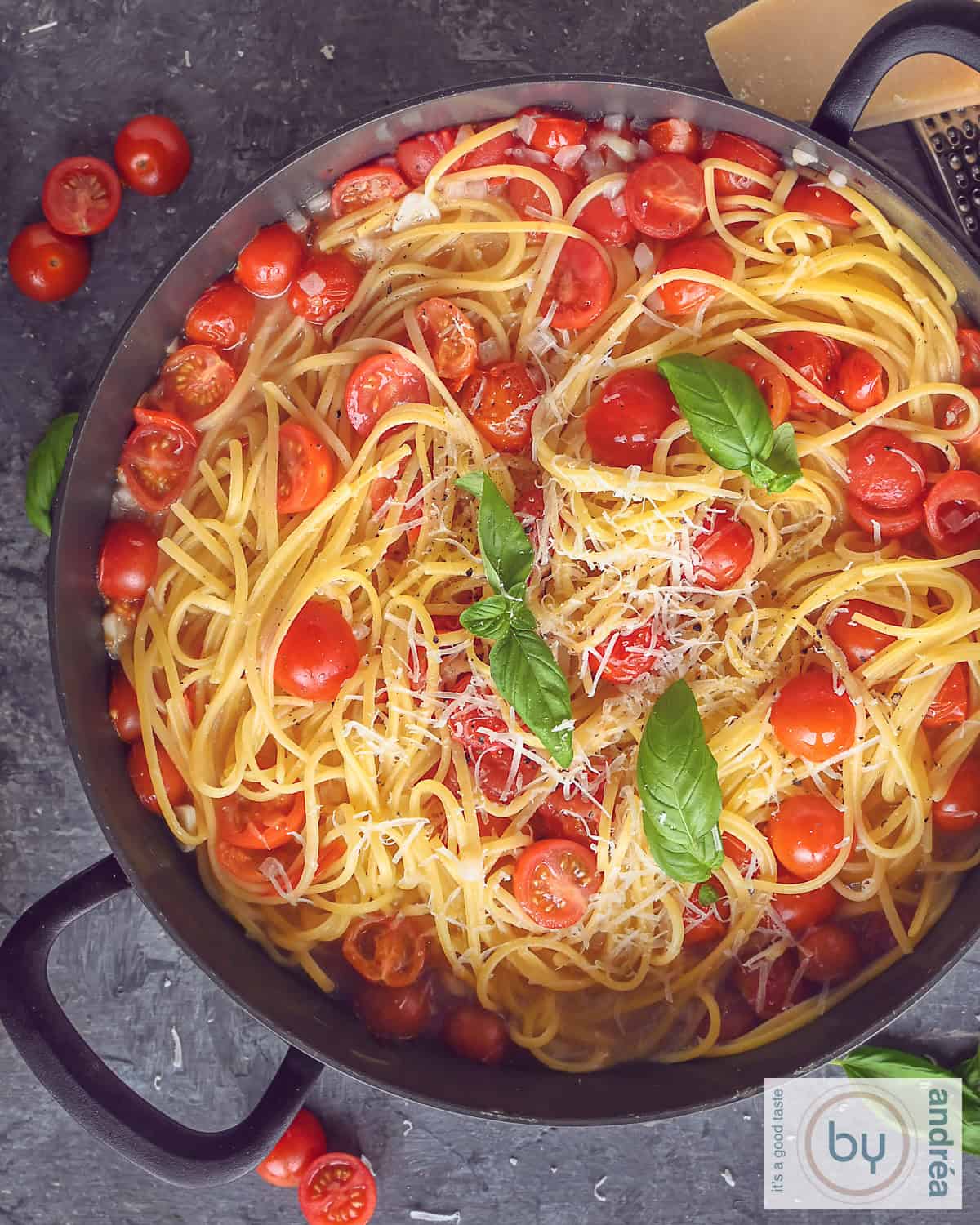 Een hoogtefoto met een roze bord met pasta, basilicum, ui, kaas en tomaten.