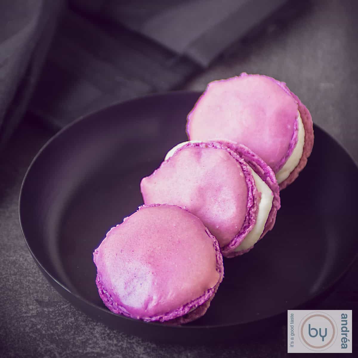 Granaatappel macarons met champagne op een donkere ondergrond op een zwart schaaltje