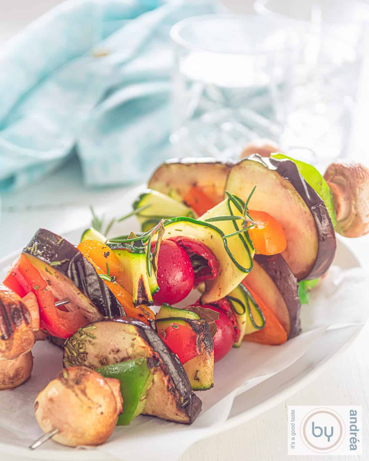 drie vegan kebabs gegrild, op een witte plaat. Een blauwe handdoek achterin