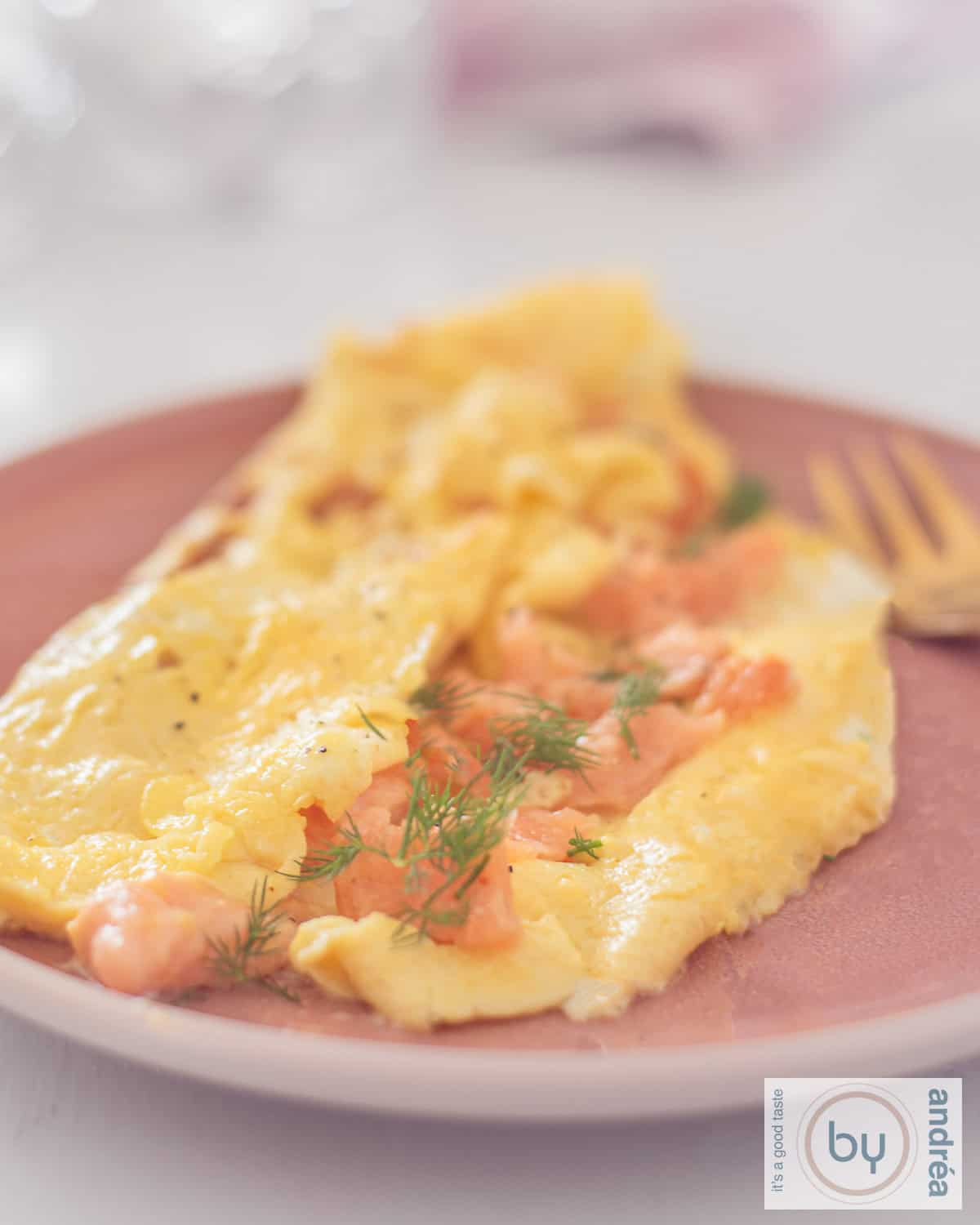 Omelet met zalmsnippers en bieslook op een roze bord