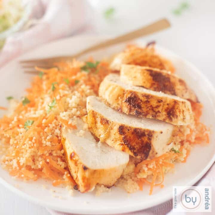 Een vierkante foto met Ras El Hanout kip met kruidige wortel couscous op een wit bord