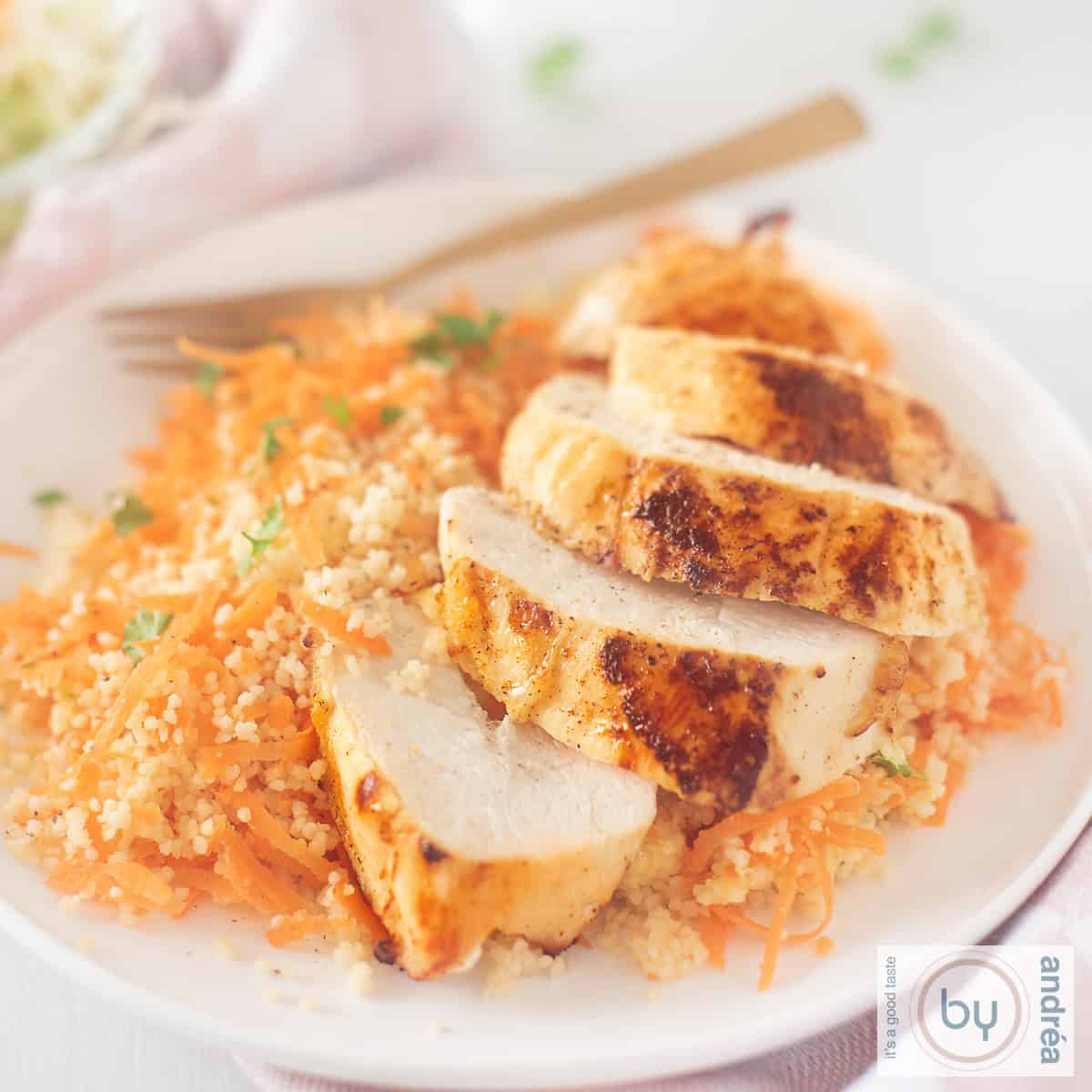 Een vierkante foto met Ras El Hanout kip met kruidige wortel couscous op een wit bord