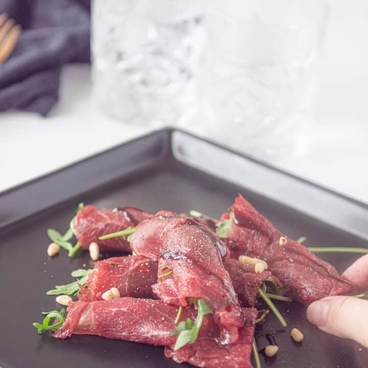 Rolletje carpaccio op een zwart bord