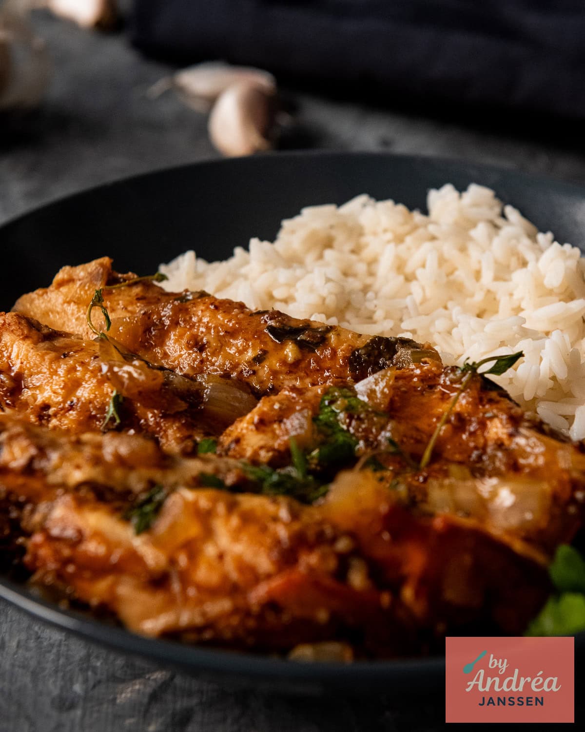Een donker bord met bruine suiker knoflook kip met rijst. 