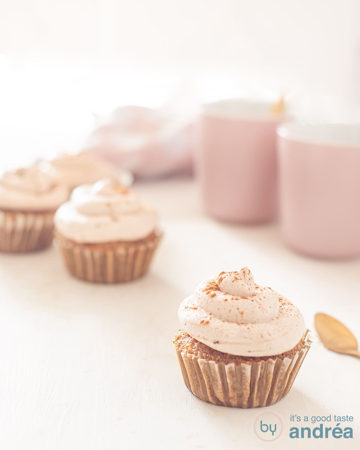 Tiramisu cupcakes op een witte ondergrond met twee roze koffiekopjes in de voorgrond