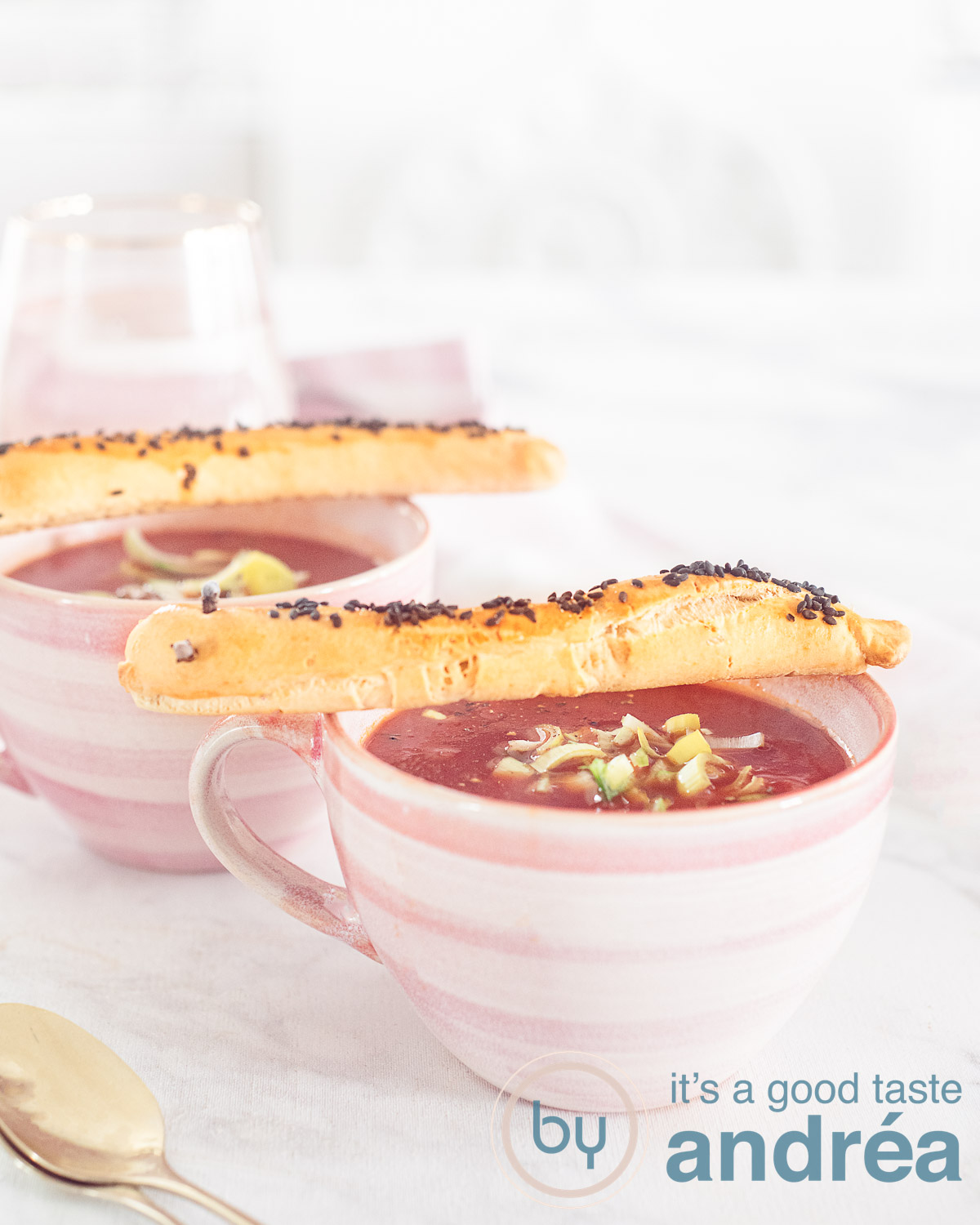 Tomaten prei soep met slissende slangen in een roze kopje op een witte ondergrond