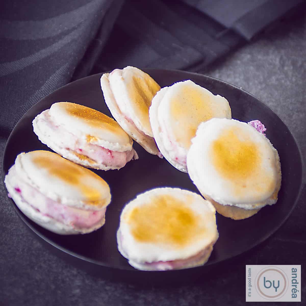 Macarons met aardbeien prosecco vulling op een zwart schaaltje op een donkere ondergrond