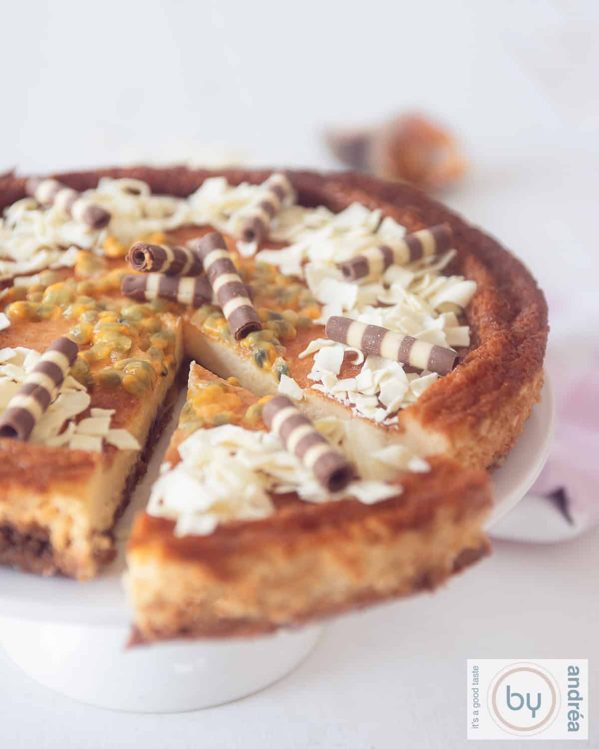 Cheesecake met passievrucht topping. Op een witte taartstandaard. Een stuk eruit gesneden