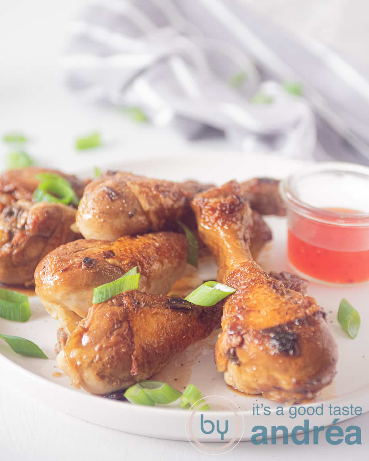 een bord met kip drumsticks in soja saus en een kommetje met chilisaus