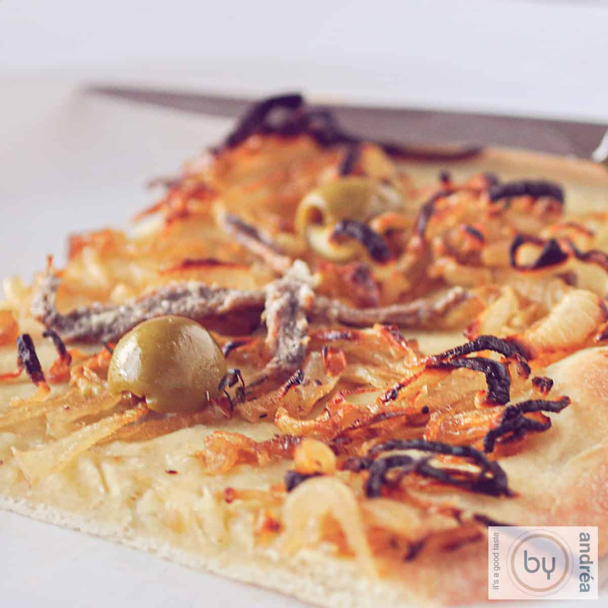 een vierkante foto met een stukje Pissaladière op een bord