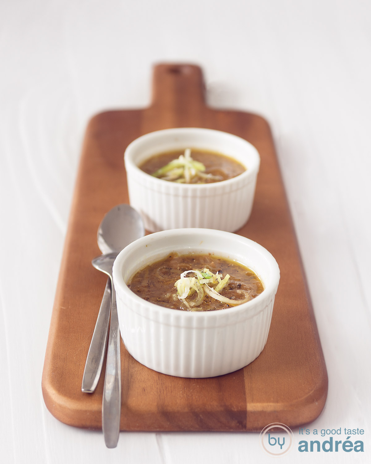 vegetarische prei kool soep in twee witte kommen op een houten plank. Een witte achtergrond