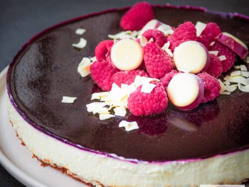 witte chocolade cheesecake met bastognekoek en bosvruchten van de zijkant gefotografeerd. Een vierkante foto
