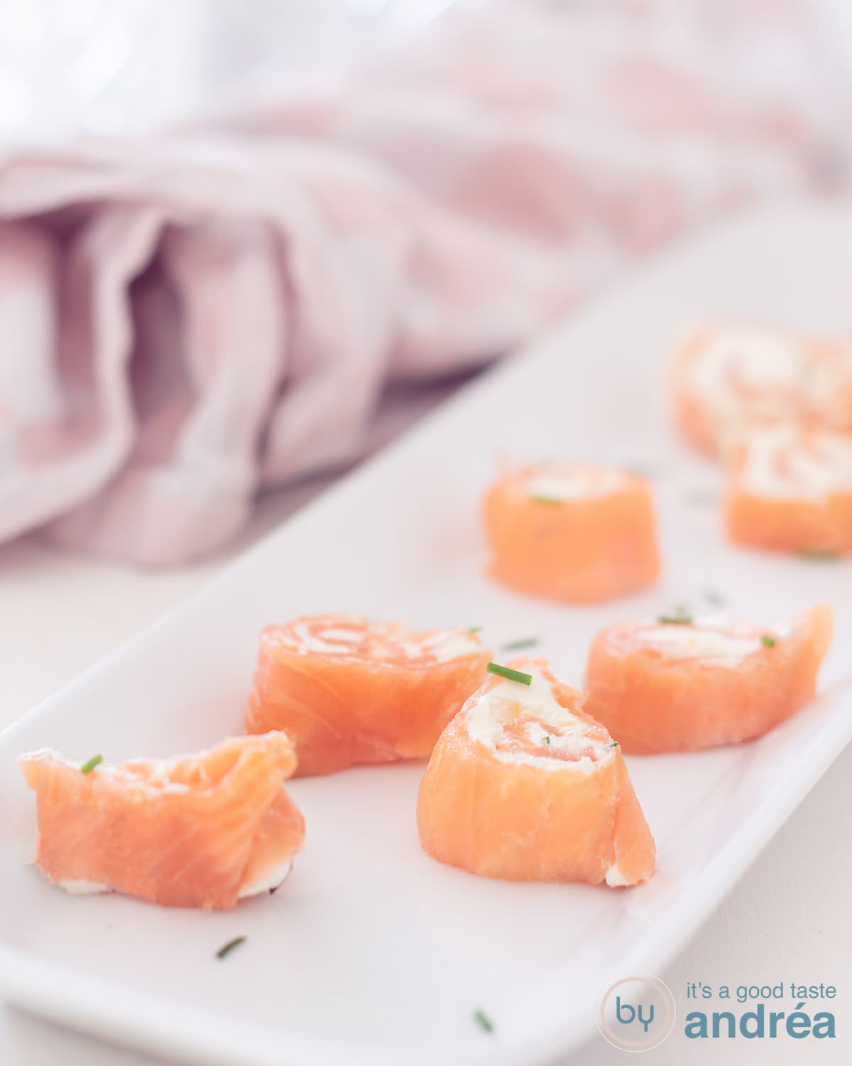 Vier zalm roomkaas rondjes op een witte schaal bestrooit met bieslook