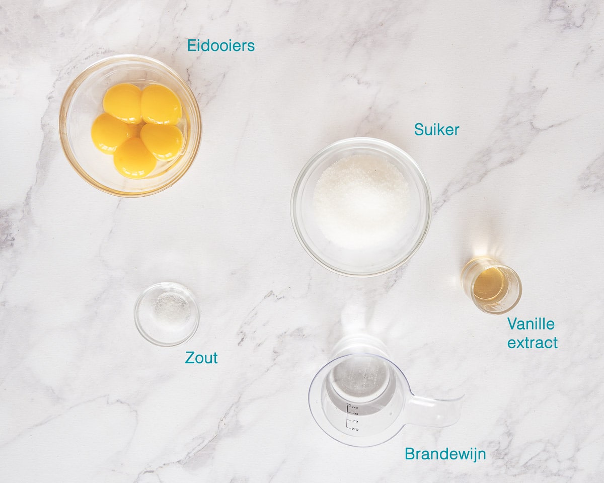 Ingrediënten Zelf Advocaat Maken, individueel gelabeld op een gemarmerd witte ondergrond.