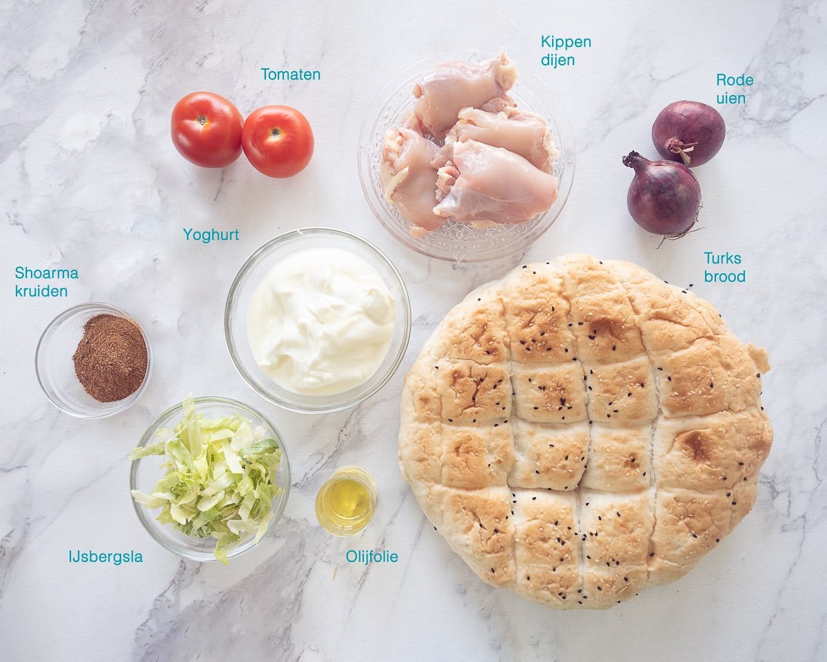 Ingrediënten Zelf Döner Kip Kebab Maken, individueel gelabeld op een wit marmeren ondergrond