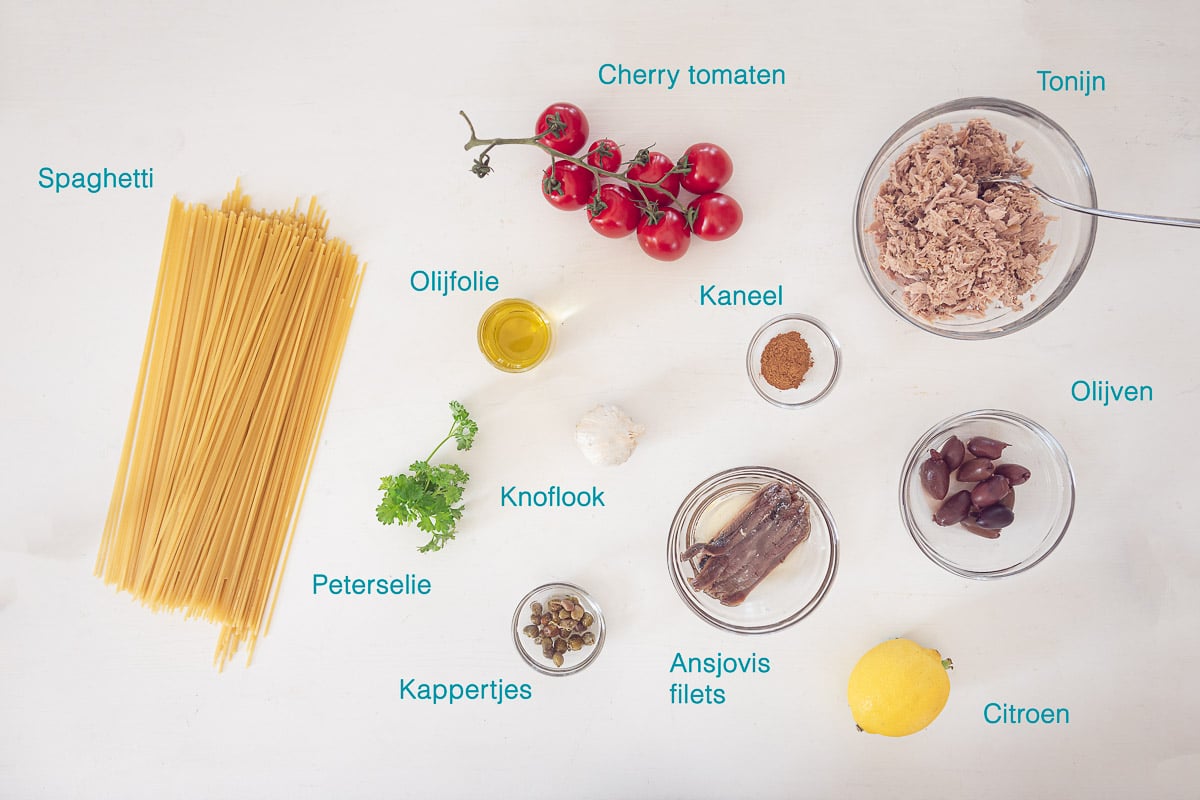 Ingrediënten Makkelijke Spaghetti Puttanesca, individueel gelabeld op een witte ondergrond.