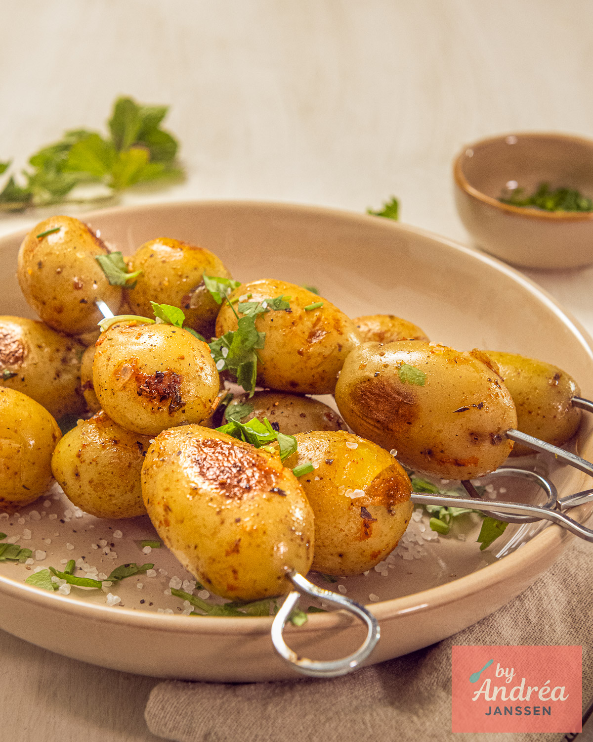 Krokante krieltjes van de barbecue op spiesjes, met goudbruine grillstrepen, zeezout en verse kruiden.