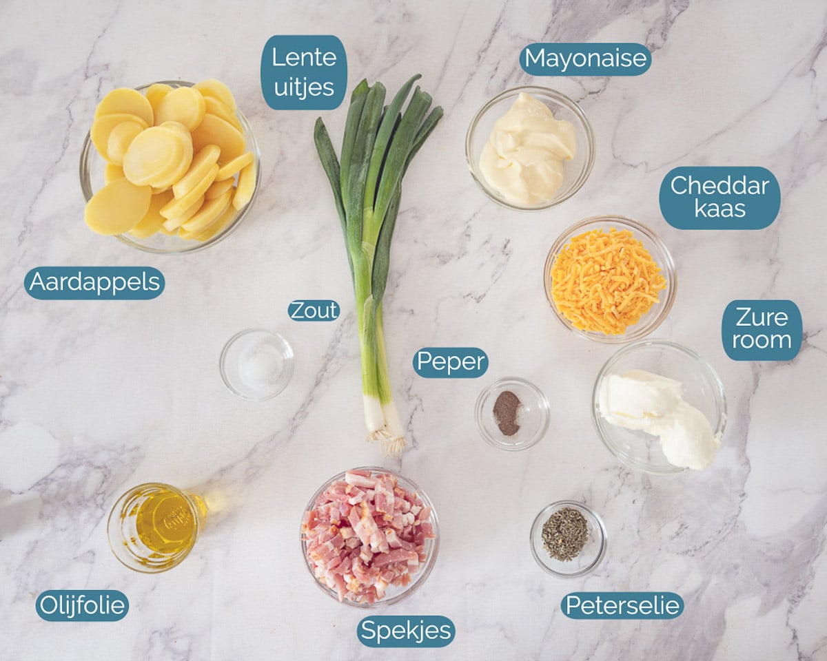 Ingrediënten Aardappelsalade met Spekjes en Kaas, individueel gelabeld op een witte marmer ondergrond