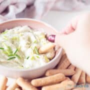 Een vierkante foto met gorgonzola dip, waar een stokje een schep eruit neemt. Stokjes liggen eromheen.