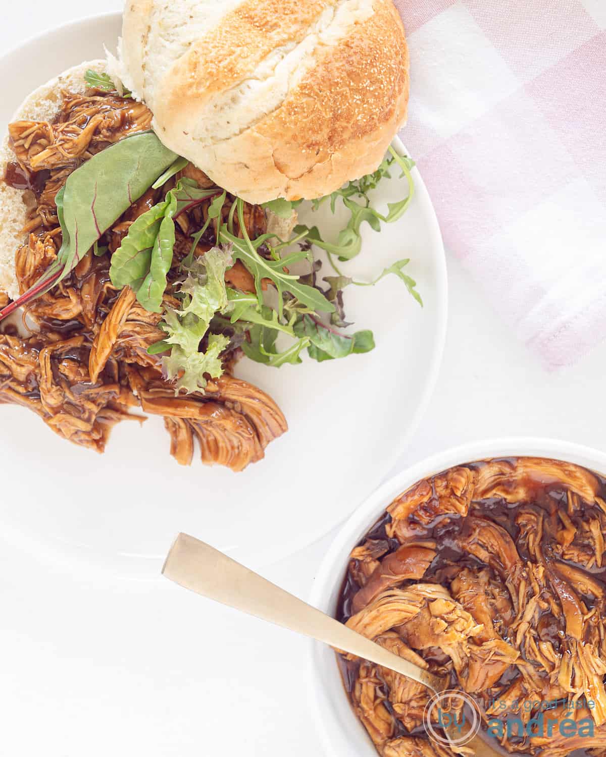 Een foto van bovenaf met linksboven een broodje met pulled chicken en sla. Rechts onderin een kom met de rest van de pulled chicken.