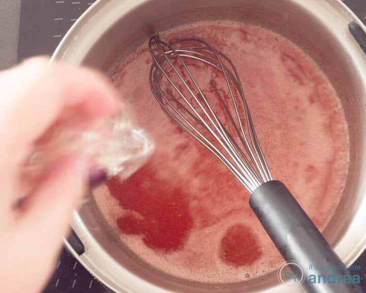 Een steelpan met aardbeiensaus waarin gelatine wordt opgelost.