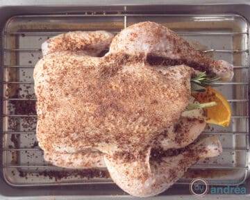 Een hele kip op een rooster in een ovenschaal. Ingewreven met kruidenrub