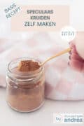 Een glazen potje met speculaaskruiden mix, een gouden lepel met een schep. Bovenin een tekst: basisrecept, speculaaskruiden zelf maken, makkelijk recept