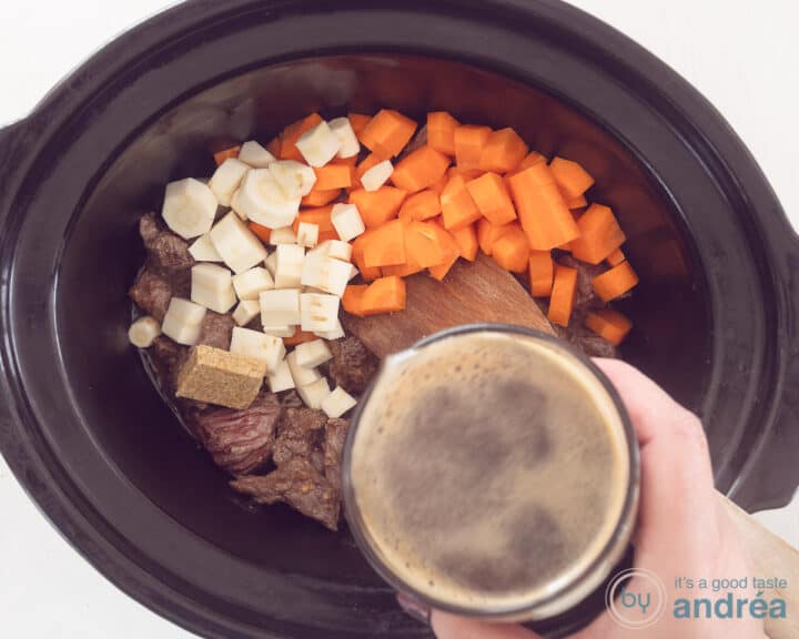 Een slowcooker gevuld met vlees, pastinaak en wortelblokjes. Bier wordt erbij geschonken