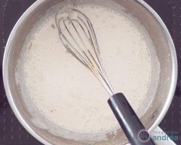 Kokosmelk in een steelpan met een garde erin