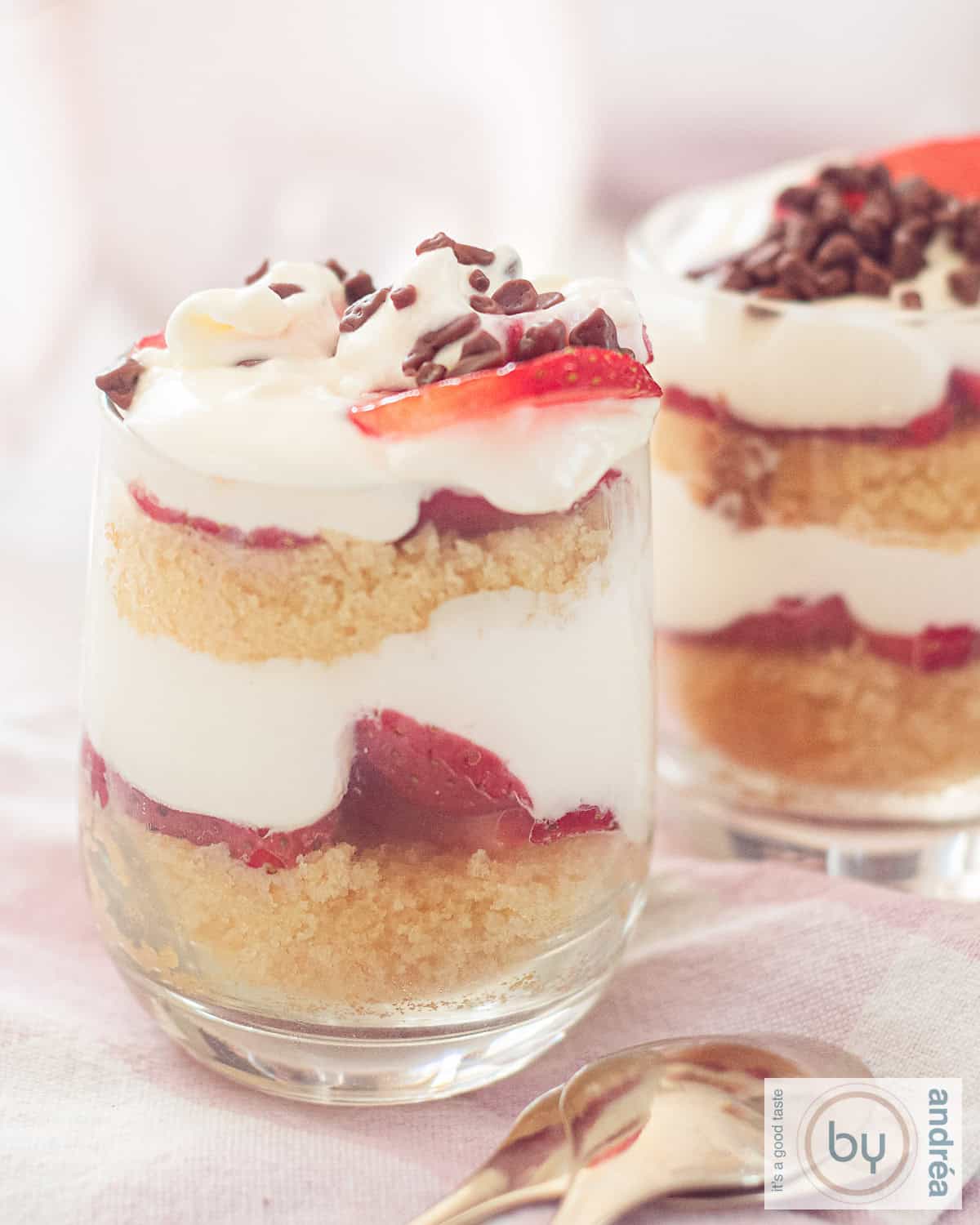 Een hoogtefoto met twee glaasjes gevuld met laagjes cake, verse aardbeien, mascarpone room afgewisseld