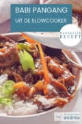 Een deel van een kom gevuld met babi pangang, rijst en een garnering van bos-ui. Extra saus wordt erover gegoten. Een tekst bovenin: babi pangang uit de slowcooker, makkelijk recept.