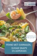 Een deel van een roze schaal gevuld met pasta, garnalen, sugar snaps en asperges. Een tekst erover: Penne met garnalen, sugar snaps en asperges, makkelijk recept.