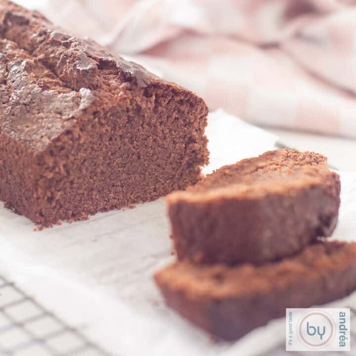 Een vierkante foto van een rek met daarop een chocoladecake waar twee plakjes cake zijn afgesneden en die ervoor liggen.