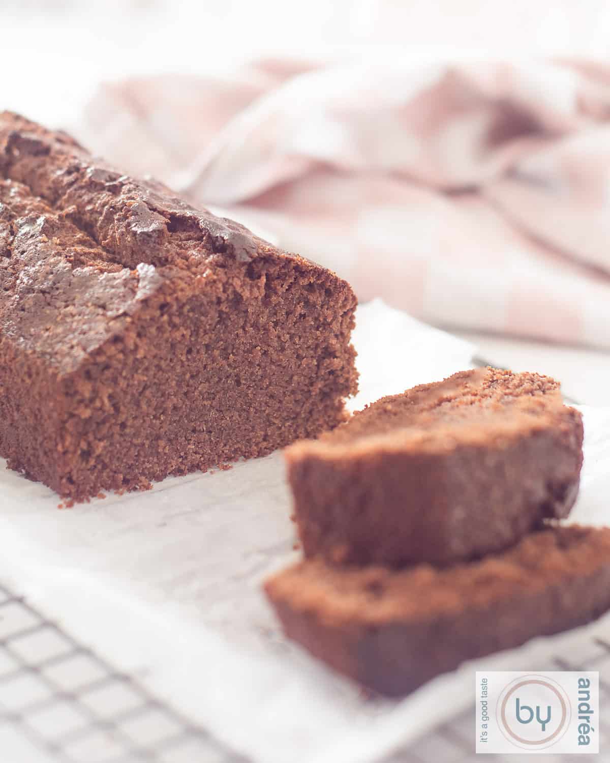 Een hoogtefoto met chocoladecake op een bakpapier op een rek waar twee plakjes vanaf zijn gesneden