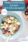 Een foto van bovenaf van een blauwe schaal met parelcouscous met feta, komkommer, rode ui, tomaat en munt. Een tekst: parelcouscous salade met feta en munt, makkelijk recept