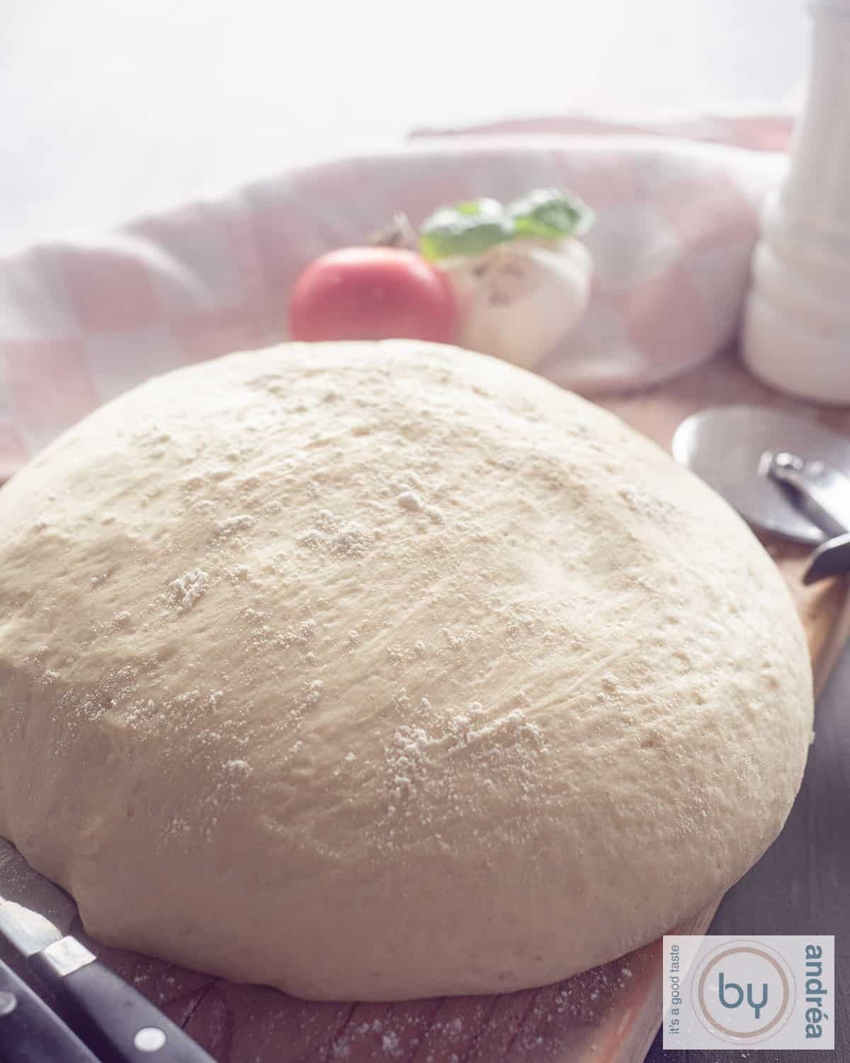 Een hoogtefoto met een bol pizzadeeg, gerezen op een houten plank.