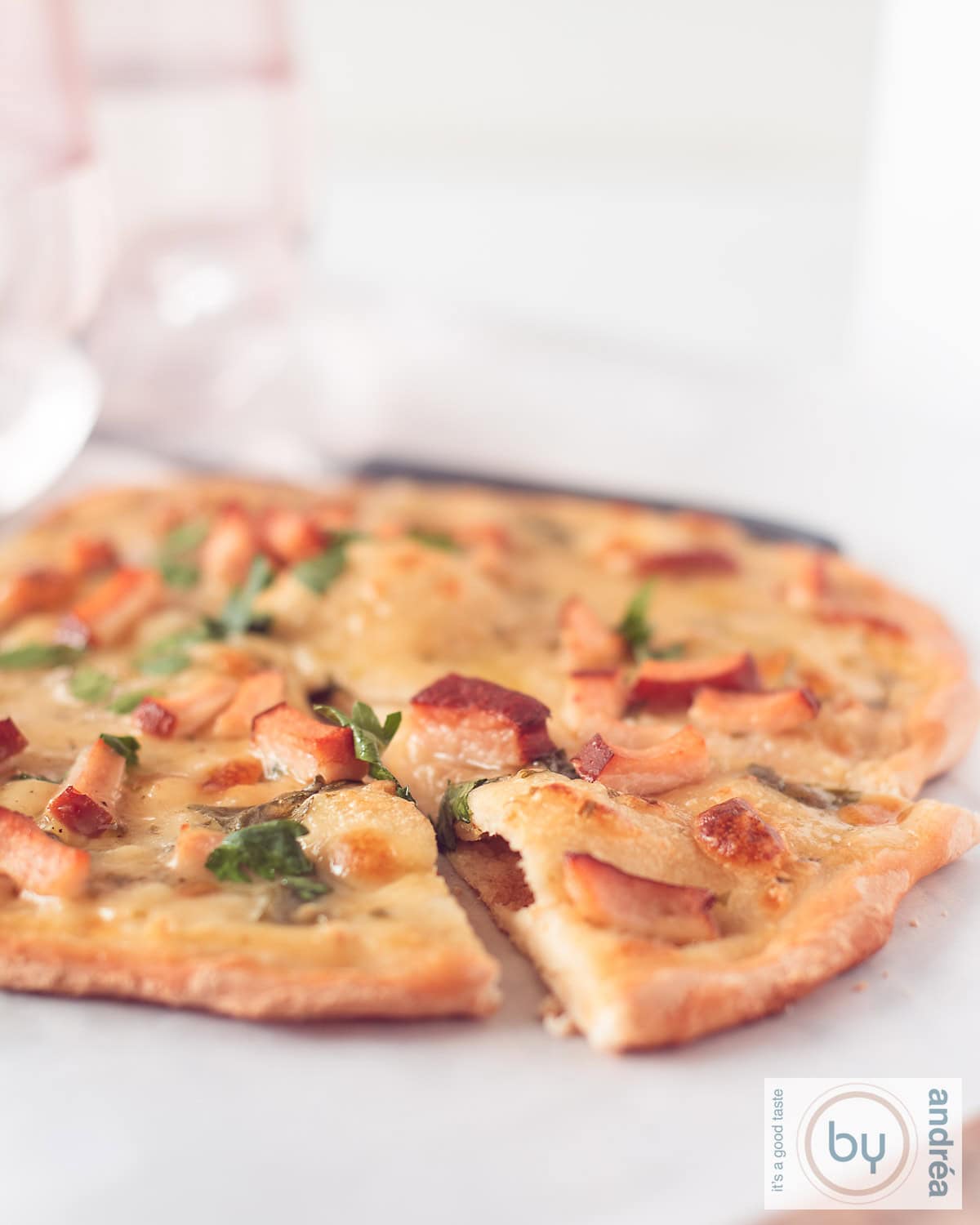 Een hoogtefoto met een pizza alfredo waar een punt uit is gesneden. Een witte ondergrond.