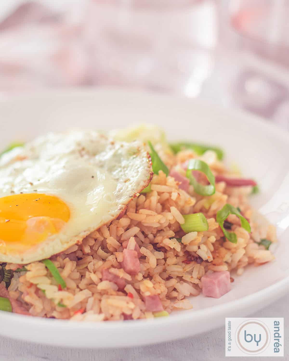 Een hoogtefoto met een diep bord met nasi goreng met ham, spek en kip en een spiegelei
