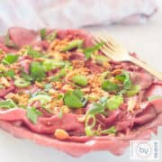 Een vierkante foto met een schaal gevuld met rosbief carpaccio salade Aziatische stijl.