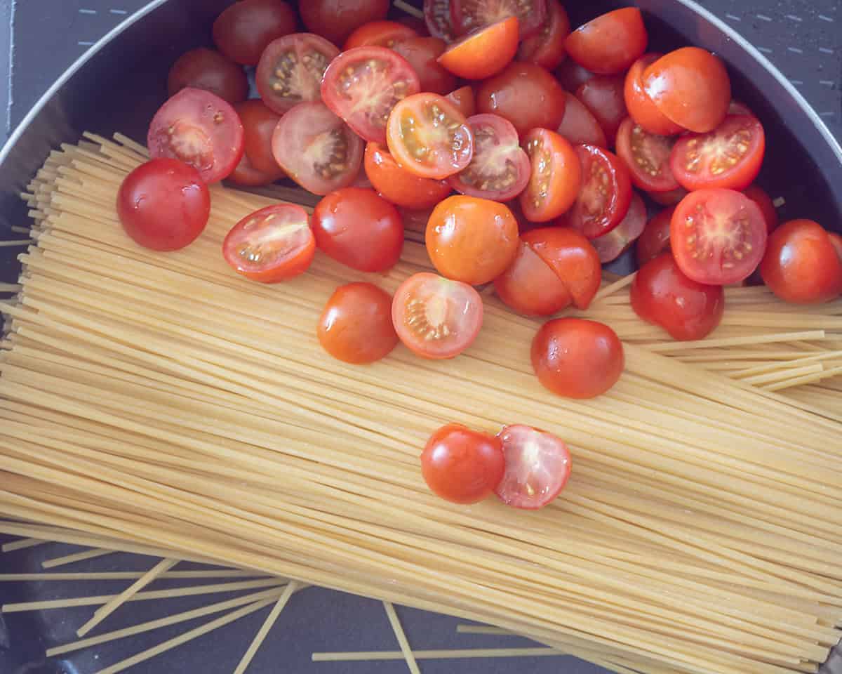 Een hapjespan met linguine pasta en gehalveerde cherrytomaten
