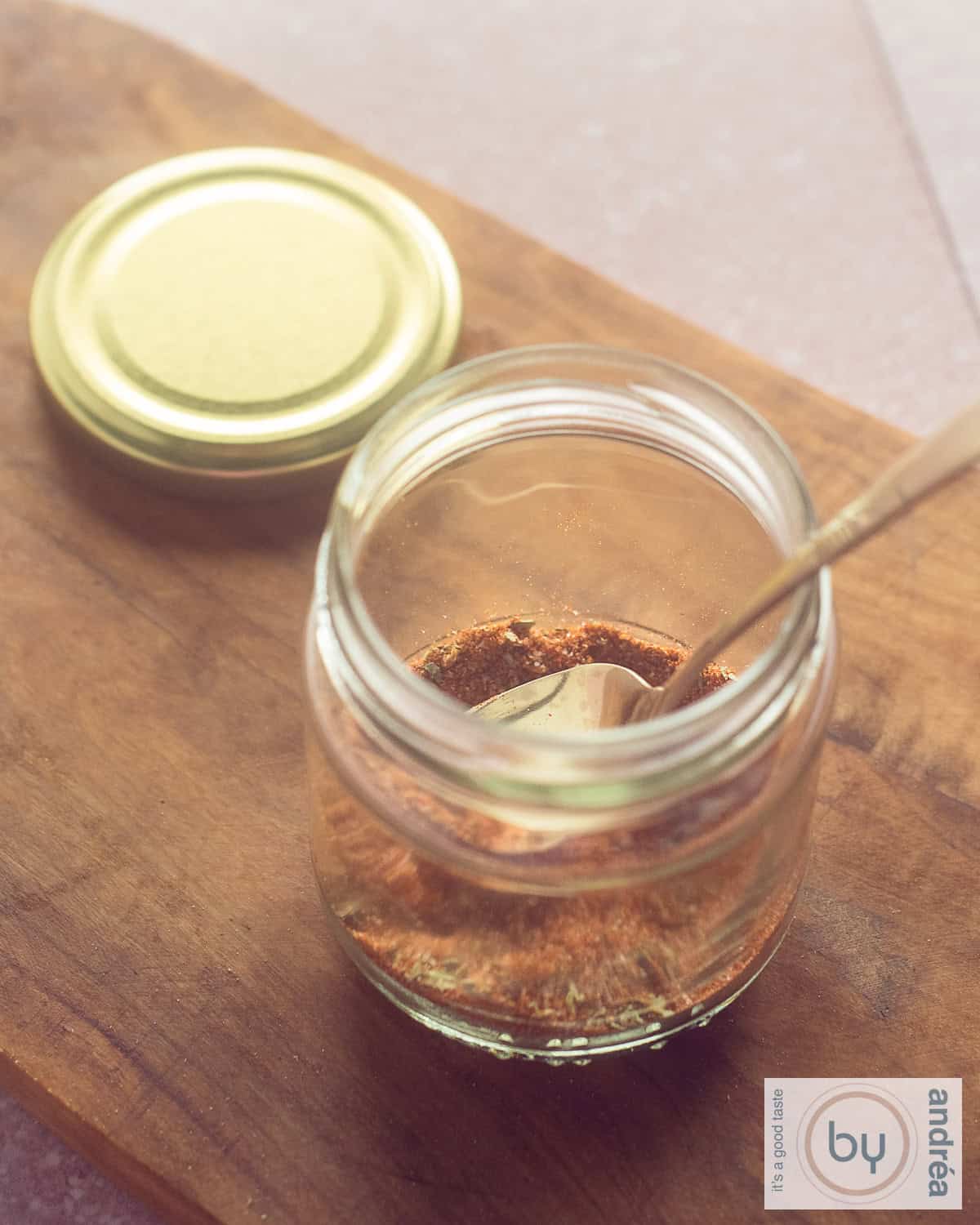 Een potje met tacokruiden op een houten plank