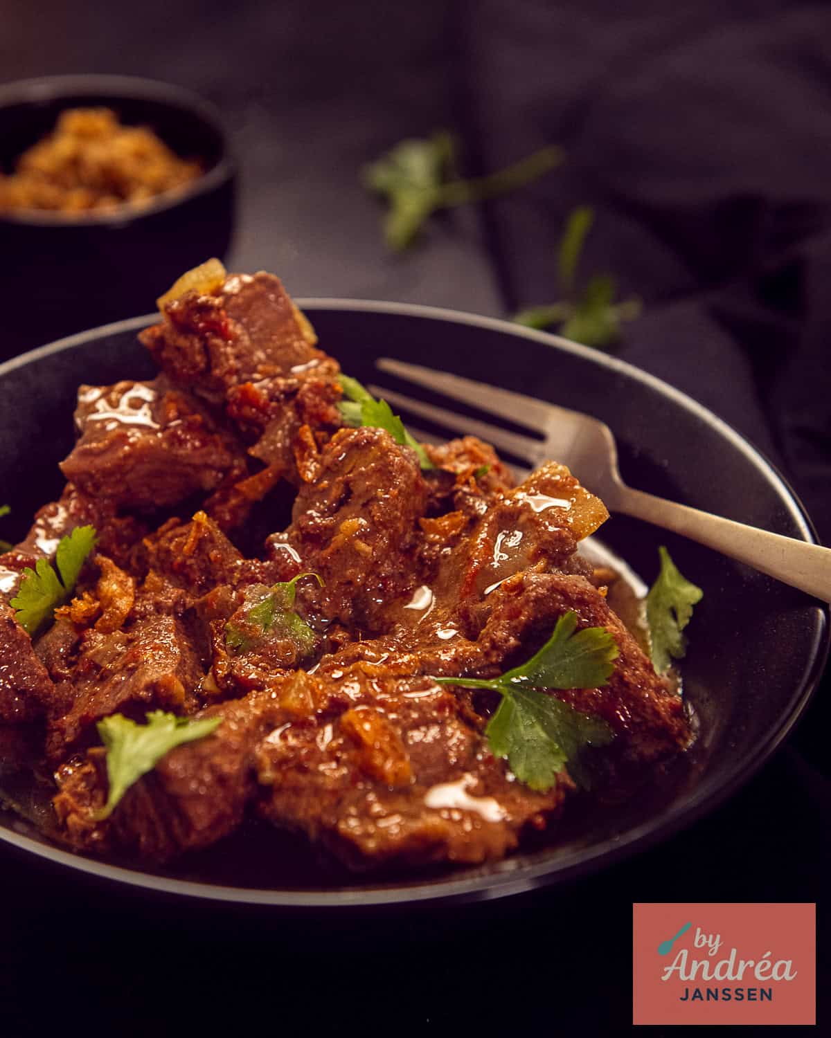 A black bowl on a black background with an Indian style curry madras slow cooker made. 
