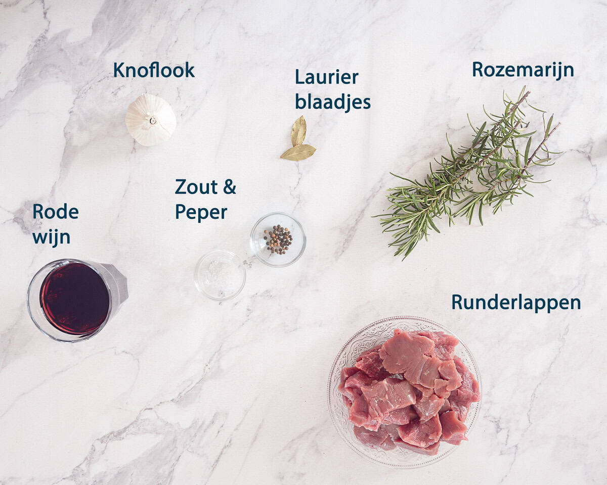 Ingredienten Slowcooker peposo heerlijk Italiaans stoofgerecht op een wit marmeren achtergrond met tekst beschrijving