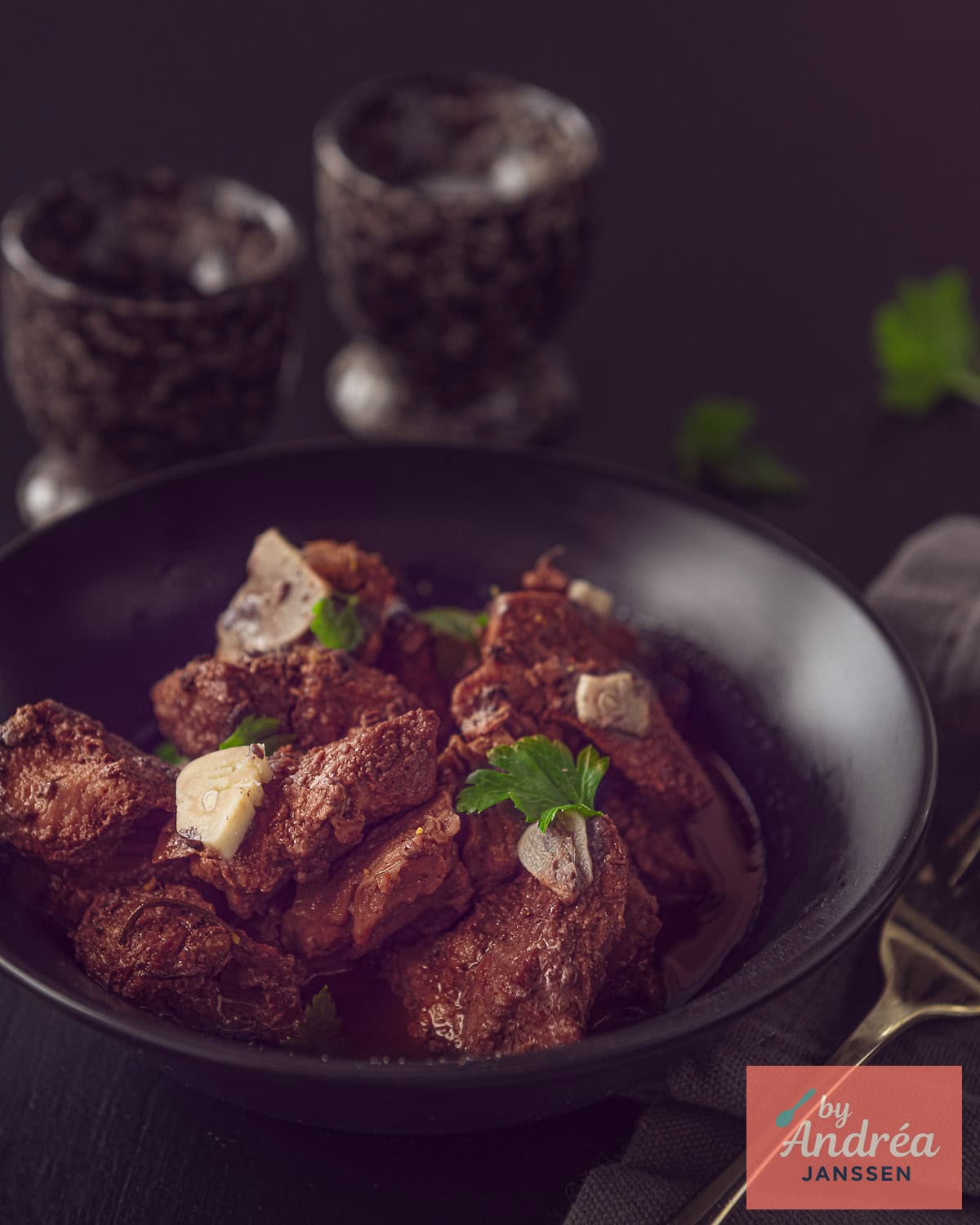 Een schaal gevuld met Italiaans stoofvlees met knoflook en rode wijn op een donkere achtergrond