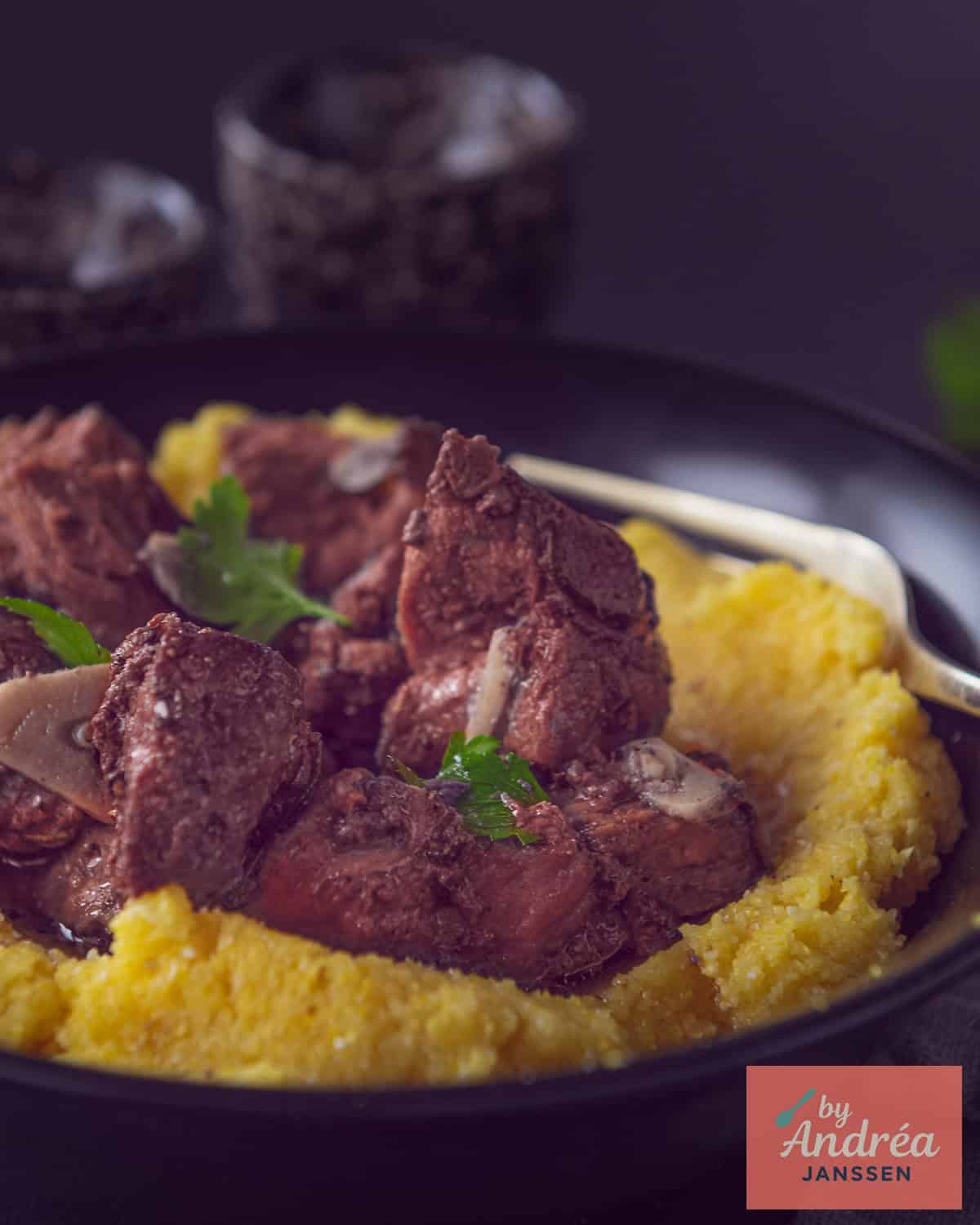 Peposo op een polenta bedje met een garnering van peterselie