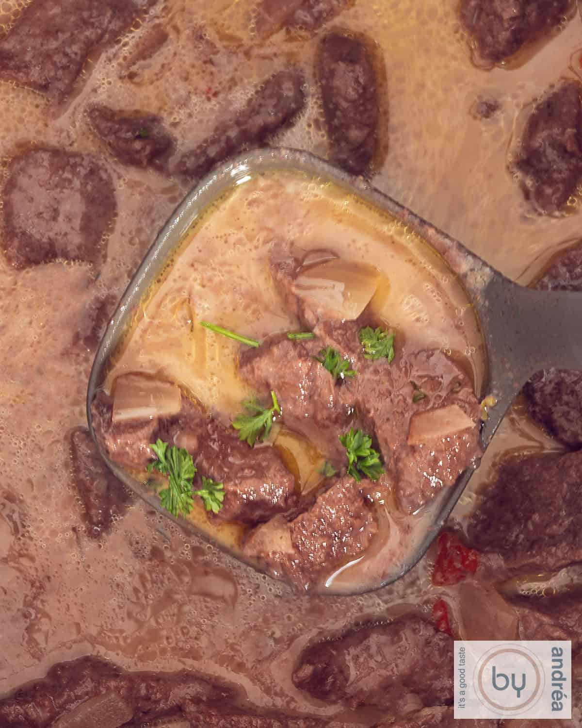 Beef Trinchado waaruit een soeplepel met stoofvlees wordt geschept.