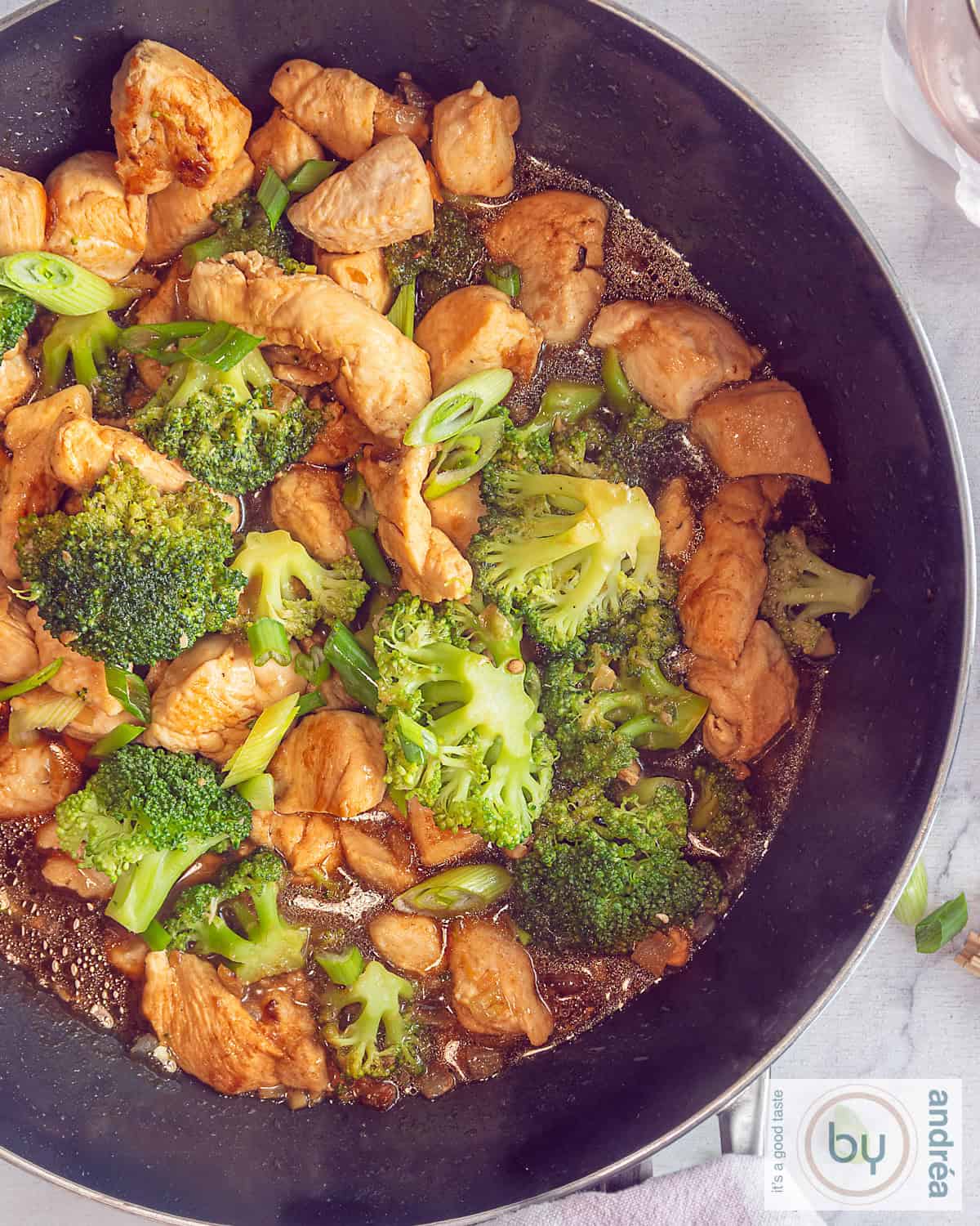 Een foto van bovenaf van ene wok met kip, broccoli en een heerlijke saus.