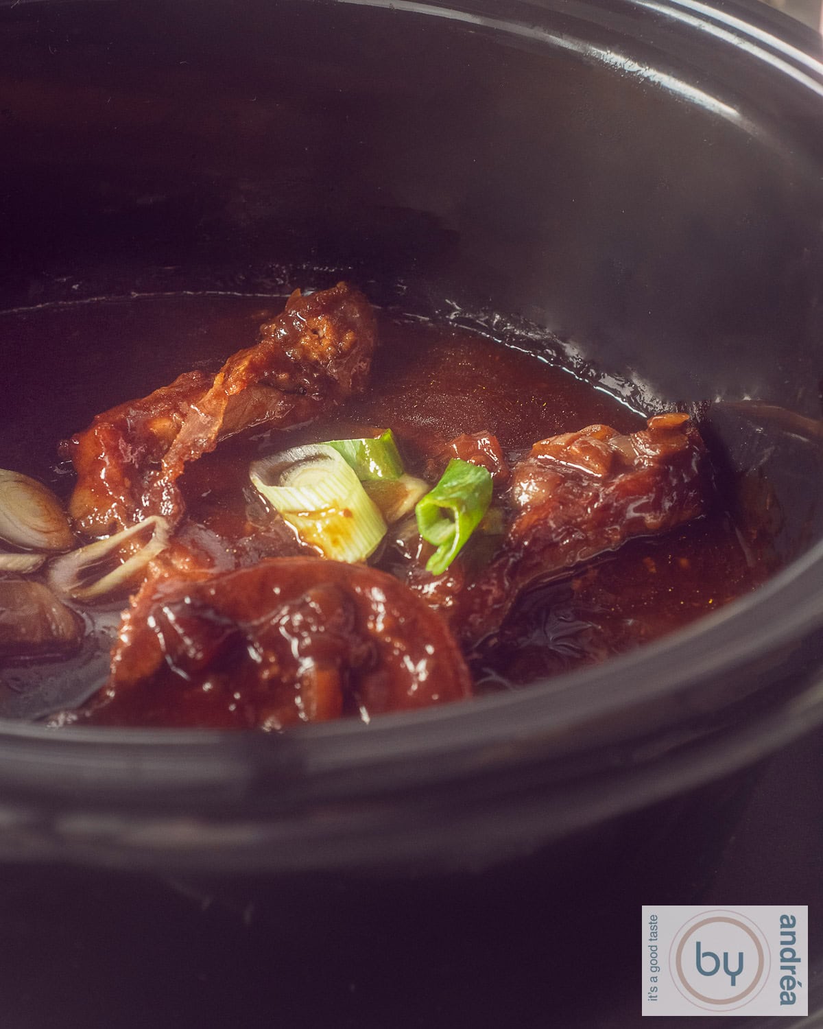 Een slowcooker gevuld met karbonades in een fluwelen sojasaus.