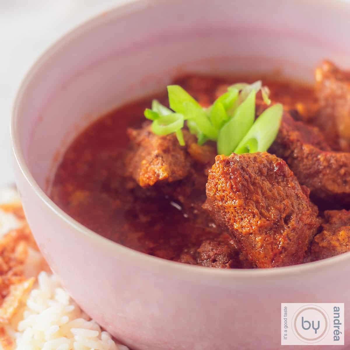 Rundvlees curry met kokosmelk in een roze kom.