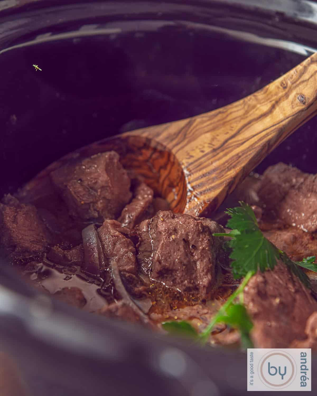 Een deel van een slowcooker met entrecote, uien en botersaus.